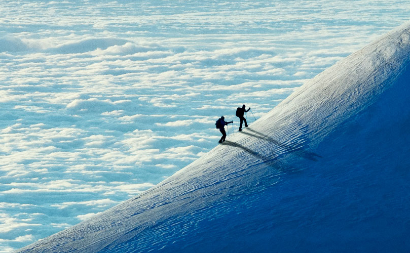 Two people climbing a snowy mountain