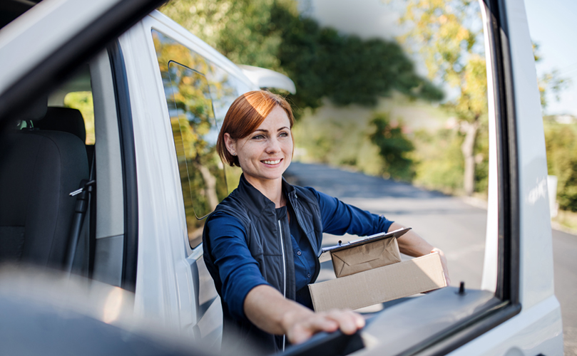 Delivery woman getting out of a car with 3 small delivery boxes