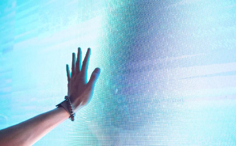 A hand touching a blue gradient touchscreen