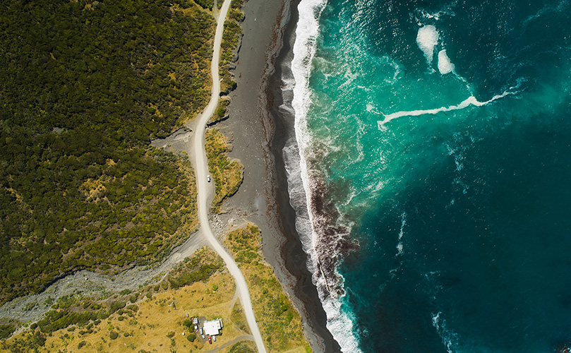 Aerial view of road passing next to coast