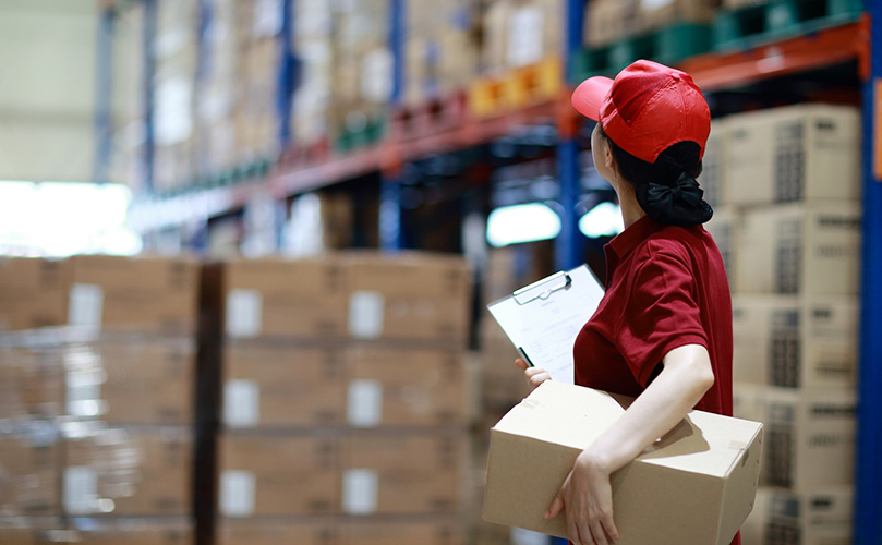 Warehouse worker holding cardboard box in logistics warehouse