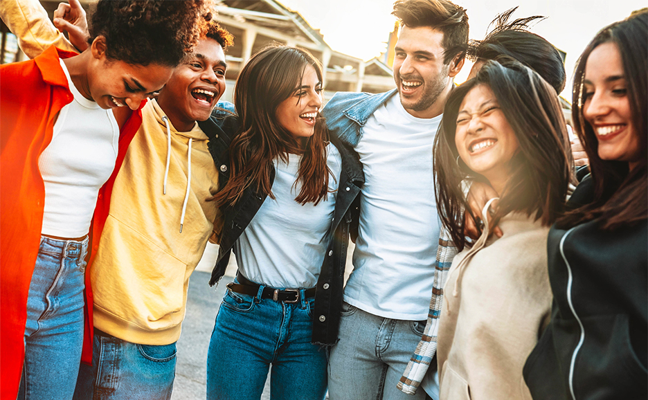 A photo of young people of diverse races and styles smiling and shoulder to shoulder.