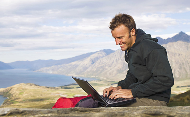 Image of a man using a laptop in nature