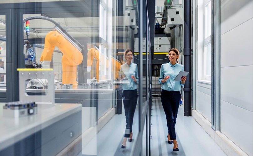 A female auditor walks through the factory checking on the automated machines