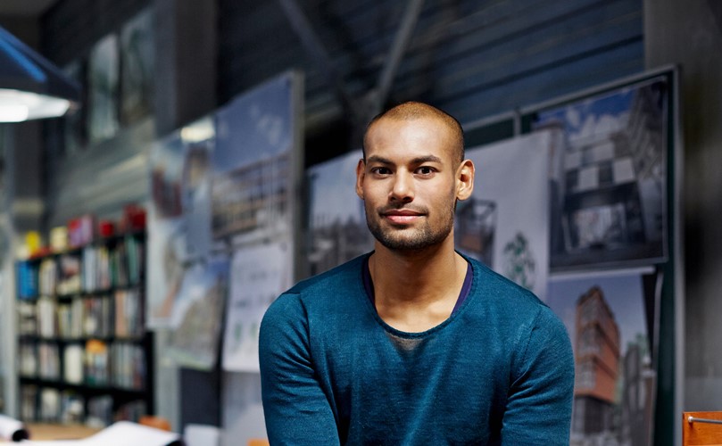 Shot of a young man looking at the camera and having an exhibition area as a background