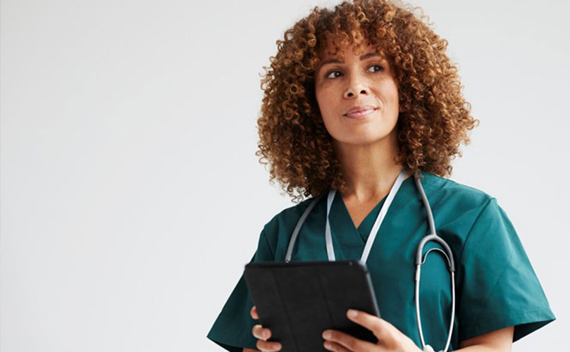 Female healthcare professional in green scrubs with a stethoscope and tablet PC