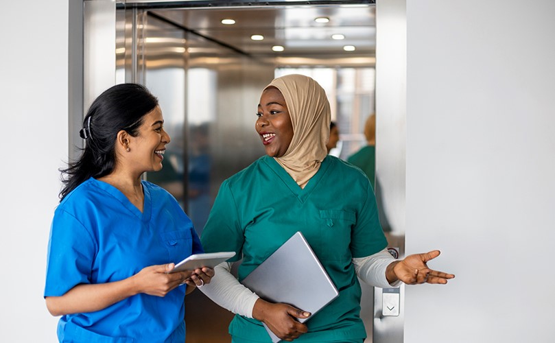 A Nurse and a Doctor walking happily out of an elevator