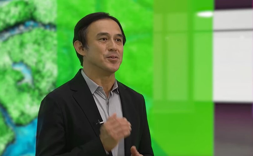 Yoshinami Takahashi, EVP at Fujitsu during a speech with a green background