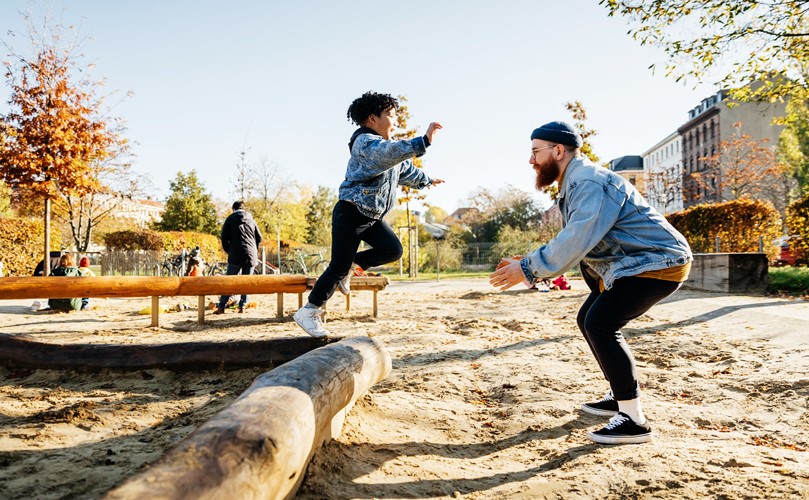 A Man and a child playing at the playground on a sunny day