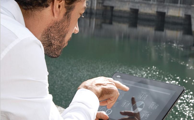  A man looking at a tablet near a lake