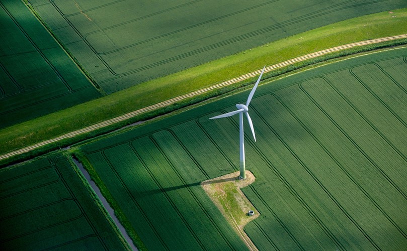  Overhead view of a green landscape with a wind energy mill 