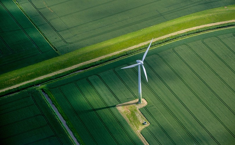 Overhead view of a green landscape with a wind energy mill