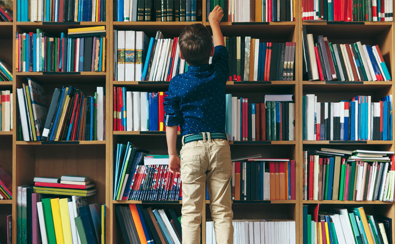  A child at a library in front of a bookshelf